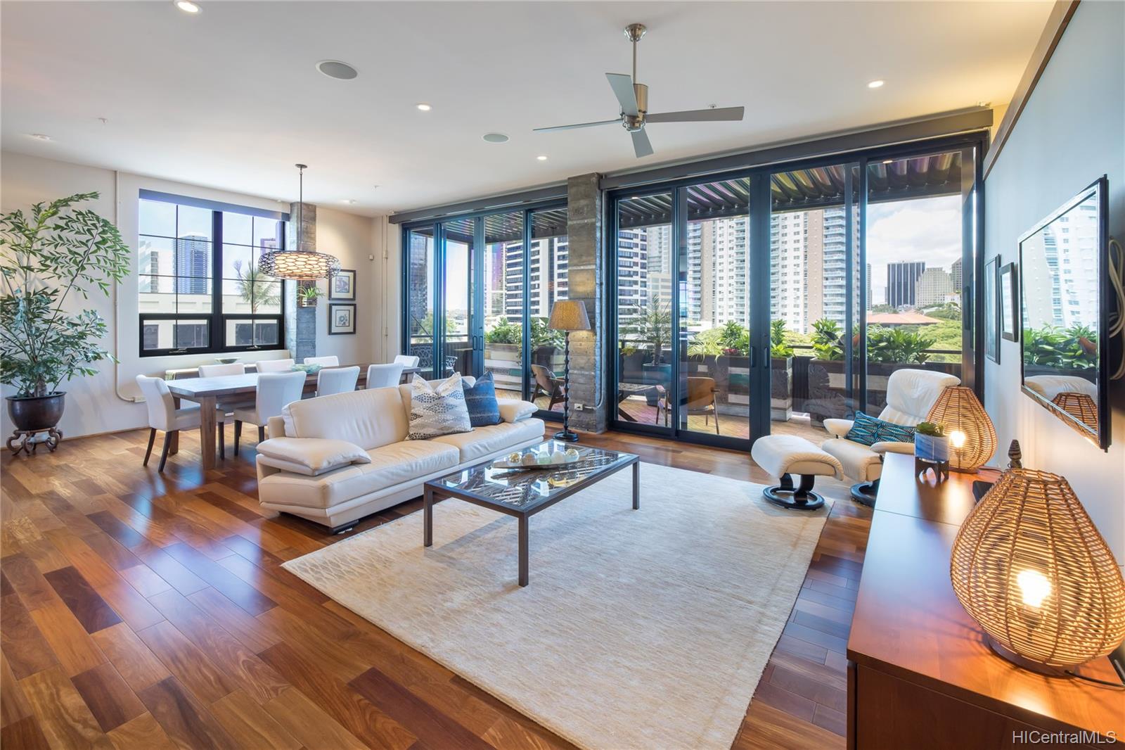 A spacious and well-lit living room with hardwood floors and neutral-toned furniture in the Vanguard Lofts Hawaii 501