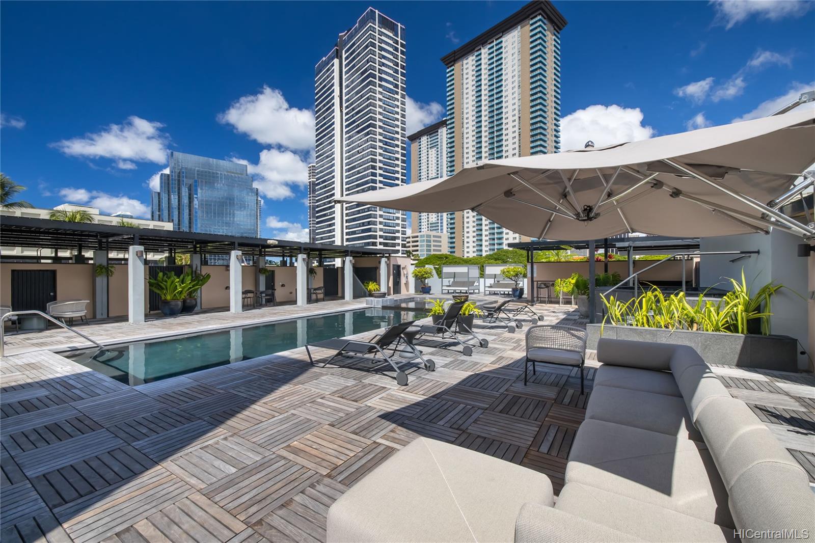 A beautiful pool deck surrounded by lush tropical foliage in the Vanguard Lofts 501 in Hawaii.